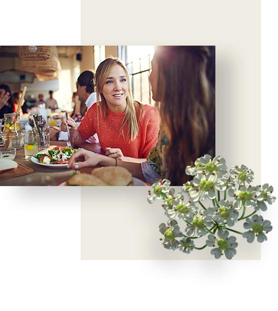 A woman wearing red blouse, is having a meal with her friend, in a casual restaurant.