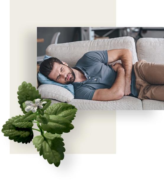 Man suffering from bloating is lying on his side, holding stomach in pain.