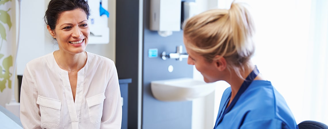 Female Physician, dressed in blue uniform is talking to her female patient.