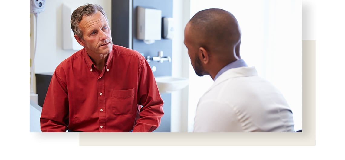 Man in a red shirt, suffering from irritable bowel syndrome talking to doctor.