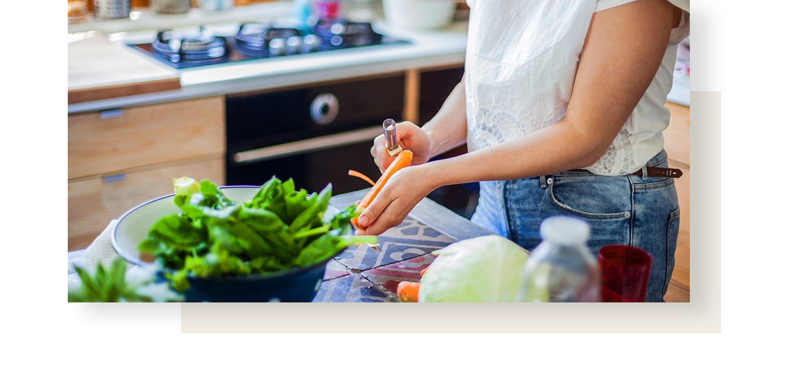 Closeup of woman hands, peeling a carrot on a kitchen counter.