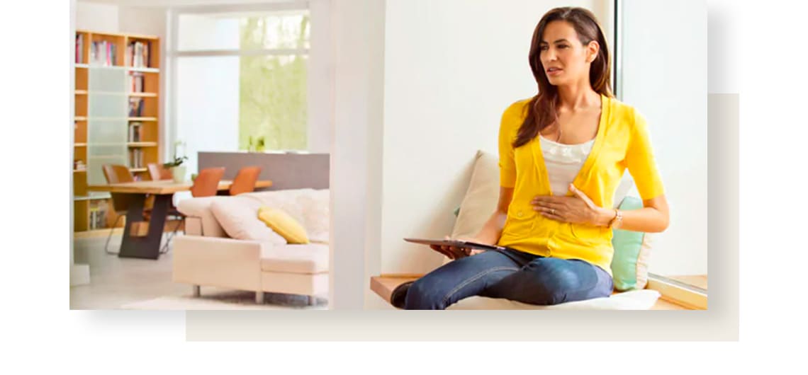 Woman wearing yellow sweater, suffering from irritable bowel syndrome