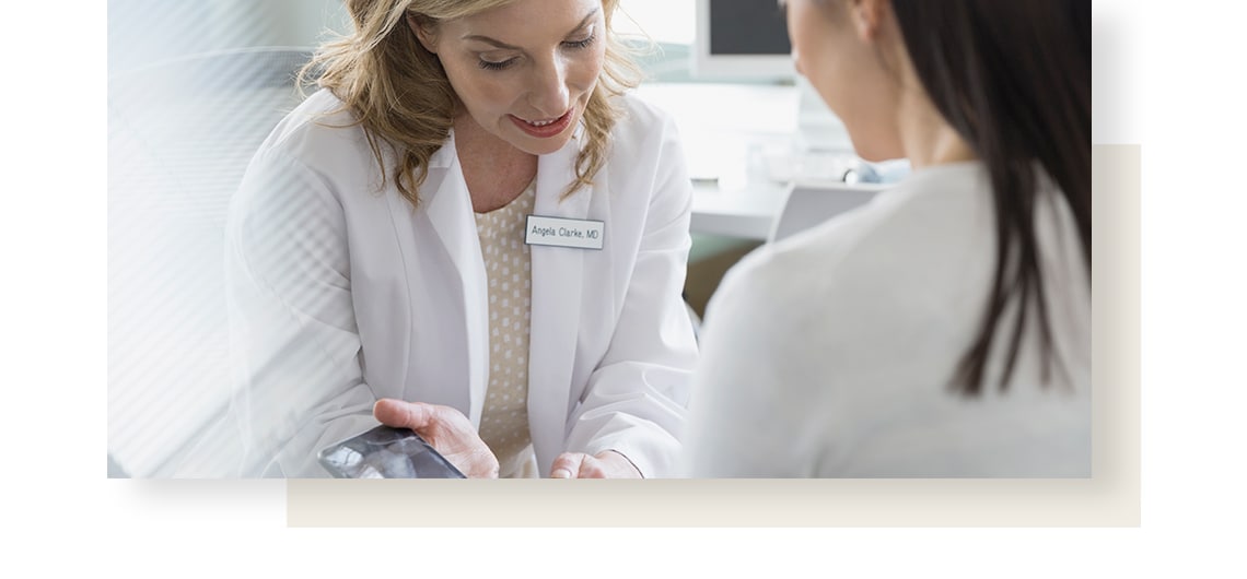 Female physician is showing sometinh on a smartphone to her patient.