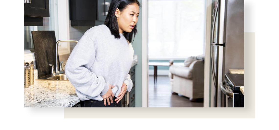 Asian woman holding her stomach in pain, caused by indigestion.