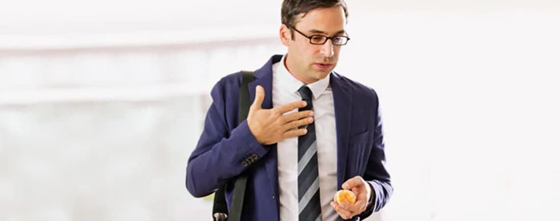 Man suffering from heartburn after eating an orange.