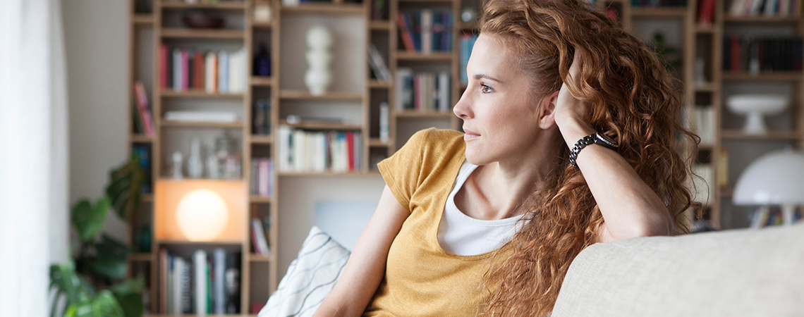 Red hair woman on a couch, looks left.