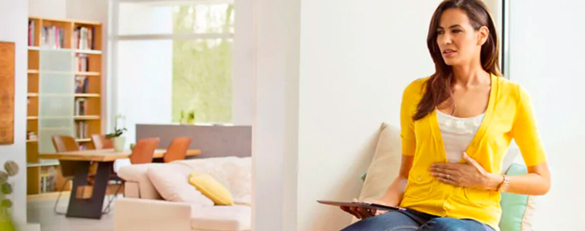 Woman wearing yellow sweater, suffering from belching.