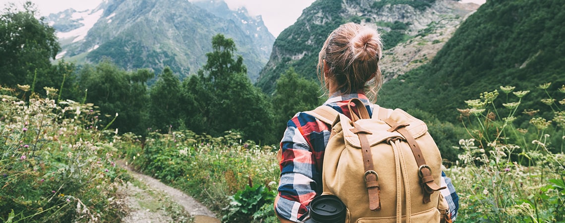 Woman walking a mountain valley, with her backpack.