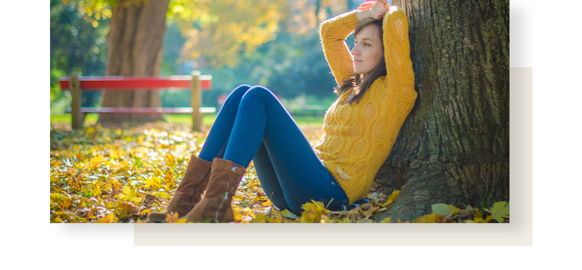 A woman in yellow sweater, sitting under the tree.