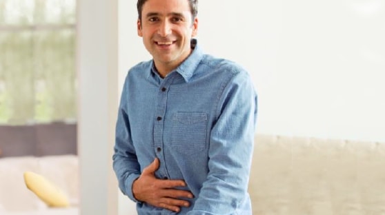 Man in blue shirt, smiling and touching stomach, happy after using Iberogast.