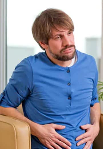 Man wearing blue t-shirt is holding his stomach.