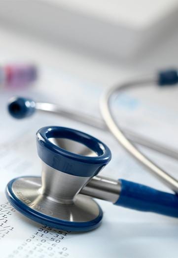 Stethoscope with blue rubber parts, lying on a sheet of data regarding nausea
