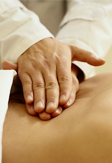 Close up of physicians hands, examining patients stomach.