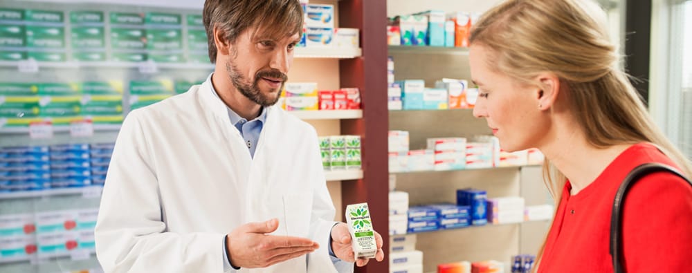 Woman in red sweater buying Iberogast from male salesperson at the pharmacy.
